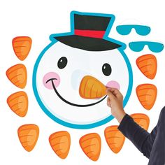 a man holding up a paper cut out of a snowman with carrots around it