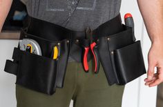 a man is holding his tool belt with tools in it and there are other tools in the pocket