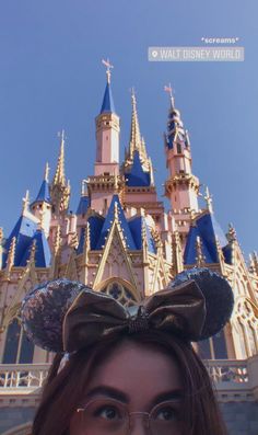 a woman wearing glasses and a minnie mouse ears headband in front of a castle