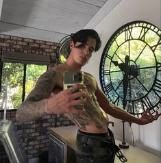 a man taking a selfie in front of a large clock with his cell phone