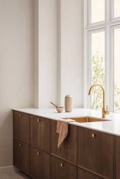 a kitchen counter with a sink, faucet and window in the back ground