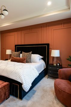 a large bed sitting in the middle of a bedroom next to two chairs and a lamp