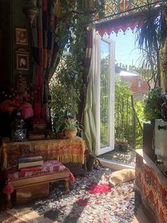 a living room filled with lots of plants and furniture next to a large open window