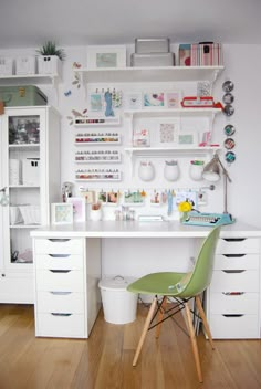 a white desk topped with lots of drawers next to a shelf filled with craft supplies