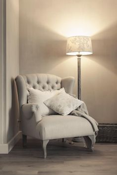 a chair with pillows on it next to a lamp