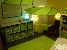 there is a green umbrella in the corner of this child's room with storage bins