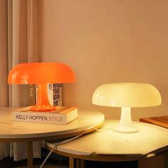 an orange lamp sitting on top of a table next to a book