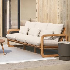 a wooden couch sitting on top of a white rug next to a chair and table