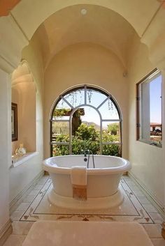 a large bathroom with an arched window and white bathtub in the middle of it