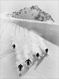 black and white photograph of skiers skiing down a mountain