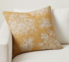 a white couch with a yellow floral pillow on it's back and the seat up