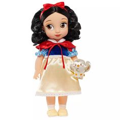 the doll is wearing a gold dress and holding a white cat in her hand with a red bow on it's head