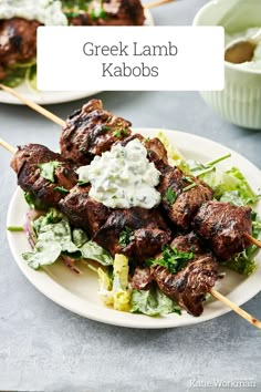 greek lamb kabobs on a white plate with lettuce and sour cream