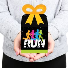 a person holding up a box with a ribbon around it and the word run on it