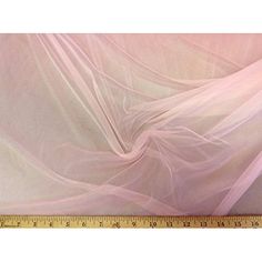 a ruler is next to a pink sheer fabric that has been draped over the top