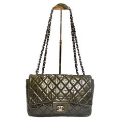 Introducing a handbag that's not just a fashion accessory but a collector's item - the Chanel 2008-2009 Metallic Patent Quilted Jumbo Single Flap in Olive Green. This stunning shoulder bag is crafted from diamond-quilted glossy patent leather, featuring leather-threaded silver-tone chain shoulder straps and a front flap with a silver-tone Chanel CC turn lock. It opens to a matte black leather interior with patch and zipper pockets. Experience Chanel's sophisticated and timeless styling in this e Designer Green Double Flap Bag, Luxury Green Double Flap Bag, Elegant Green Bag With Double Flap, Elegant Green Double Flap Bag, Green Evening Bag With Double Flap, Green Double Flap Evening Bag, Green Chanel Bag, Chanel Jumbo Patent, Dream Bag