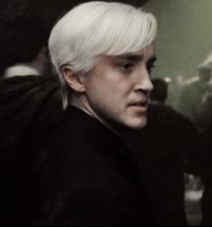 a man with white hair wearing a black coat