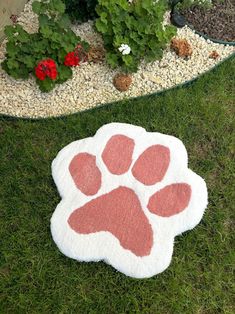 a pink and white rug with an animal paw on it in front of some flowers