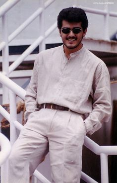 a man in sunglasses standing on the steps of a boat with his hands in his pockets