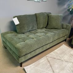 a green couch sitting on top of a carpet next to a white rug in a living room