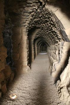 a long narrow tunnel with rocks on both sides and light coming from the end at the end