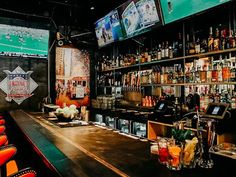 a bar with lots of liquor bottles on the shelves and televisions above it,