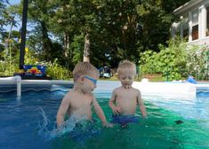 two young boys are playing in the pool