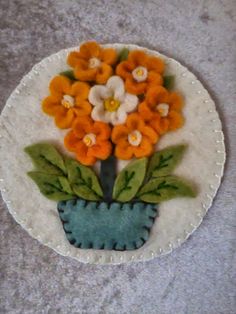 a blue vase with orange and white flowers in it sitting on a gray tablecloth