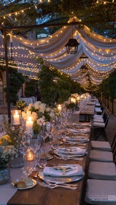 an outdoor dining table set up with candles and place settings for dinner guests to enjoy