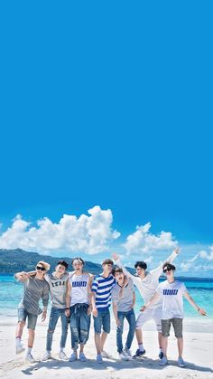 a group of young men standing next to each other on top of a sandy beach