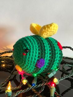 a crocheted stuffed animal sitting on top of a table next to christmas lights