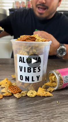 a man sitting at a table in front of a cup filled with cereal and chips