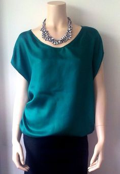 a mannequin wearing a green top and black skirt with a necklace on it