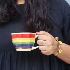 a woman holding a rainbow colored coffee cup