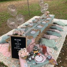 a picnic table set up with balloons, plates and confetti