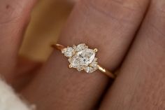 a woman's hand with a yellow gold ring on it and an oval shaped diamond in the middle