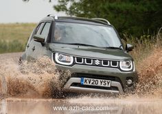 the front end of a green jeep driving through water