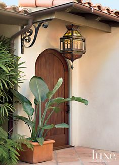 a house with a potted plant in front of it and a light on the door