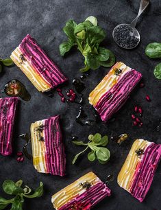 four slices of cake with pink and yellow frosting on top, surrounded by greens