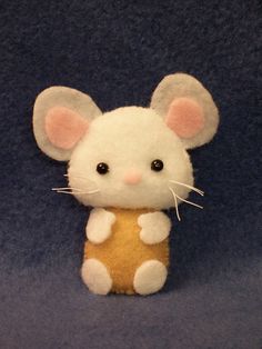 a small stuffed mouse is posed on a blue background