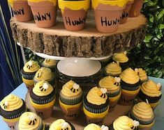 cupcakes with yellow frosting and bees on them are arranged in front of a tree stump