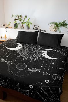 a bed covered in black and white bedspread with sun, moon and planets on it