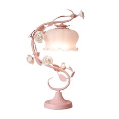 a pink table lamp with flowers and leaves on the base, against a white background