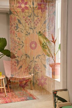 a room with a chair, rug and curtain in the corner next to a potted plant