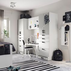 a white bedroom with black and white accessories on the bed, desk and dressers