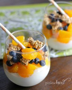 two glasses filled with yogurt, granola and fruit