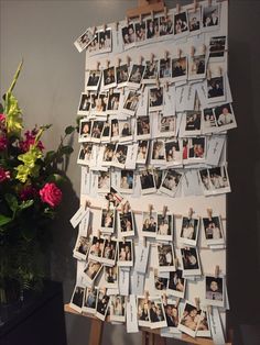 a bunch of pictures hanging on a wall next to a vase with flowers in it