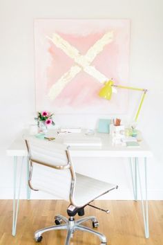 a desk with a white chair and a painting on the wall behind it in an office