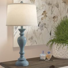 a blue lamp sitting on top of a wooden table next to a vase filled with flowers