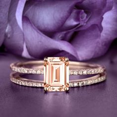 an engagement ring and wedding band with a pink rose in the background